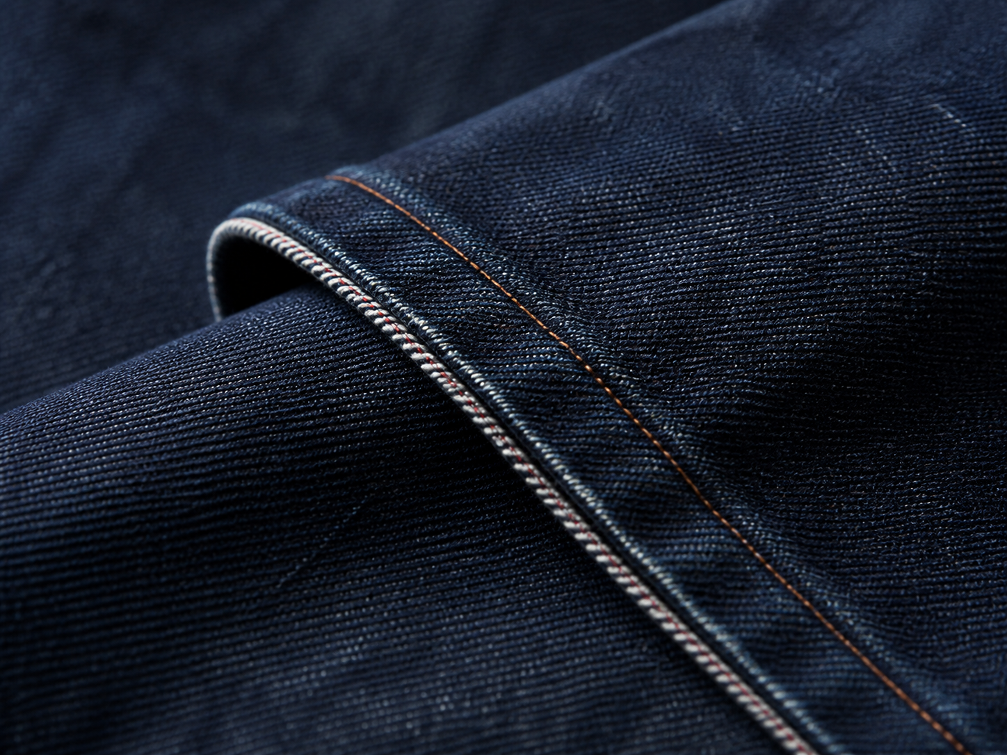 Close detail of unbranded indigo denim fabric and copper stitching